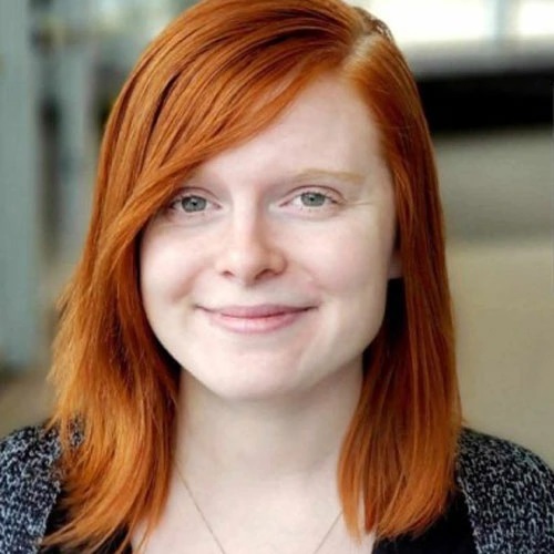 A picture of a White woman with bright red hair smiling gently at the camera.
